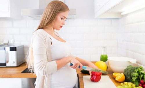 Беременная женщина готовит еду на кухне