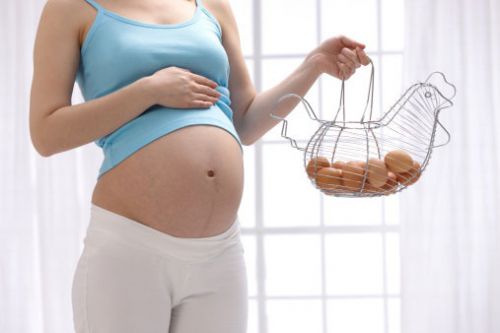 Беременная женщина держит корзинку с яйцами