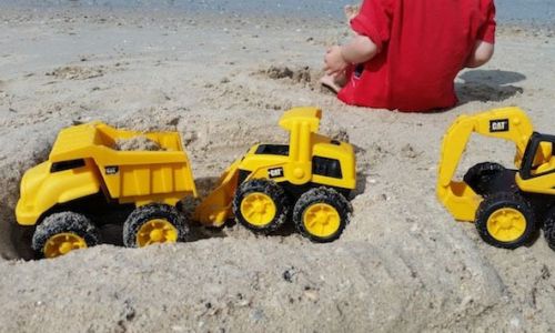 Игрушечные машины на песчаном берегу